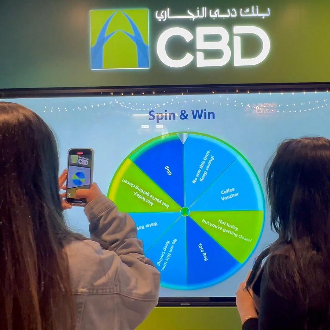 People playing a multi-level interactive financial literacy game at a brand activation event in Dubai, learning how to save and invest money.